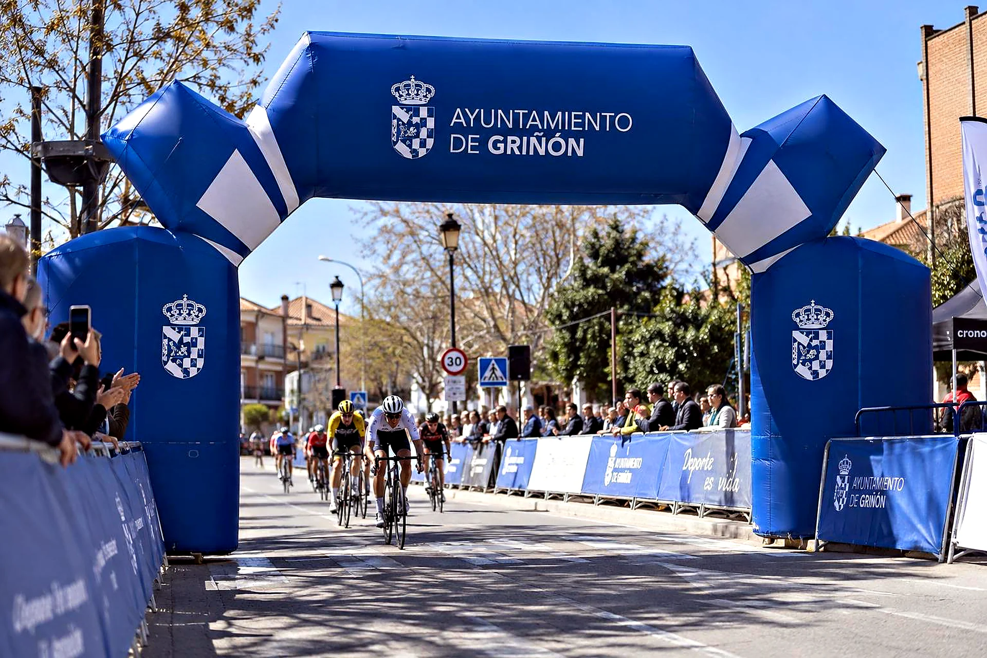 Llegada de una carrera ciclista bajo el arco hinchable azul del Ayuntamiento de Griñón